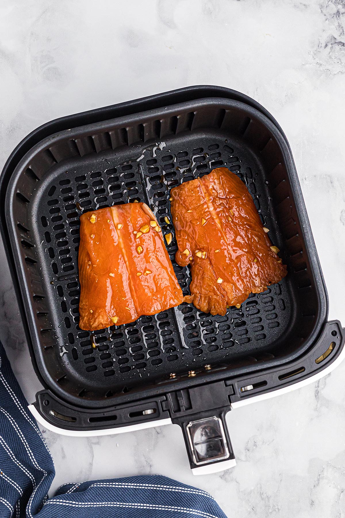 marinated salmon fillets in an air fryer basket