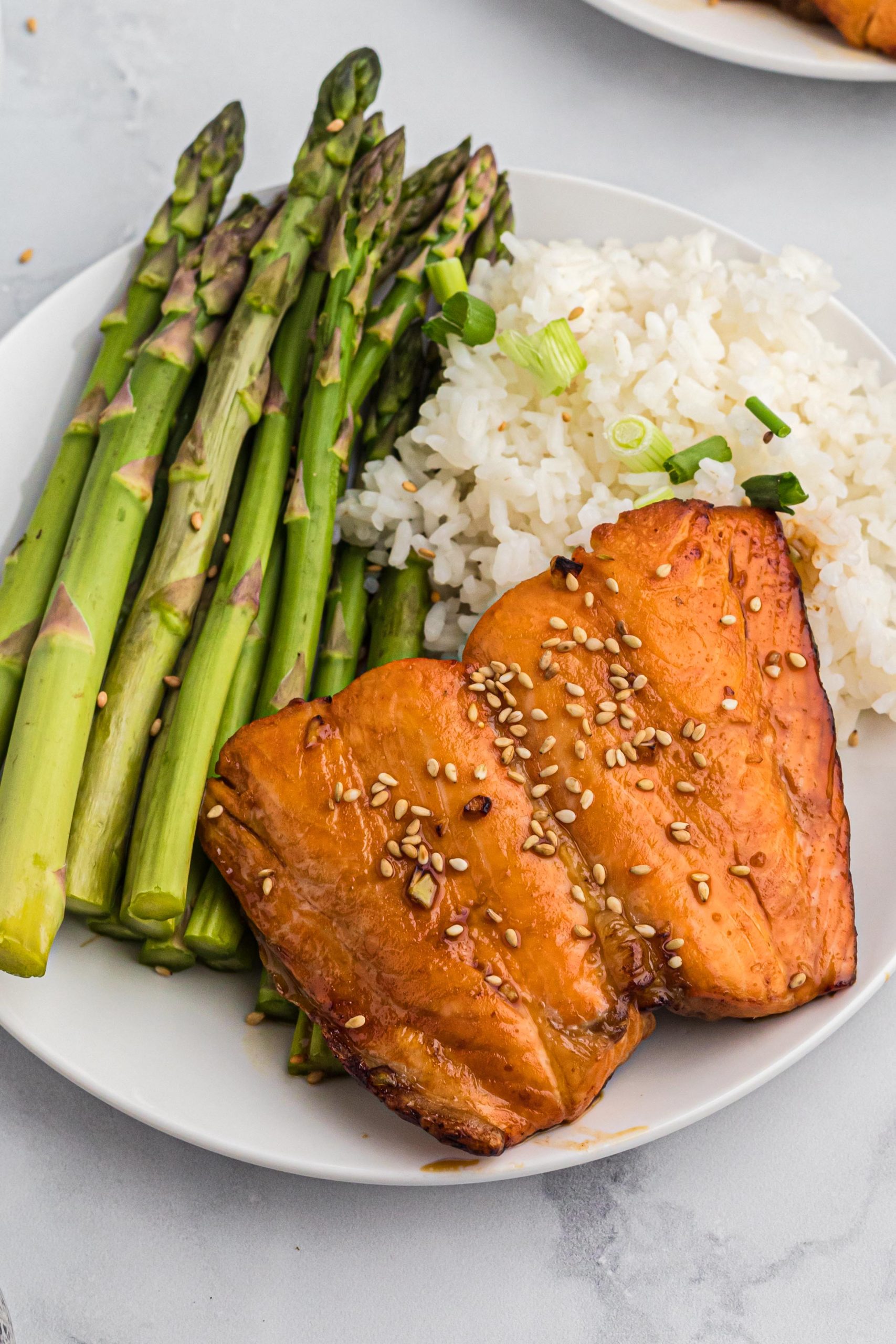 Asparagus, rice, and salmon on a small white plate.