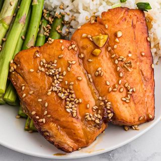 Close up of two pieces of teriyaki salmon on a white plate