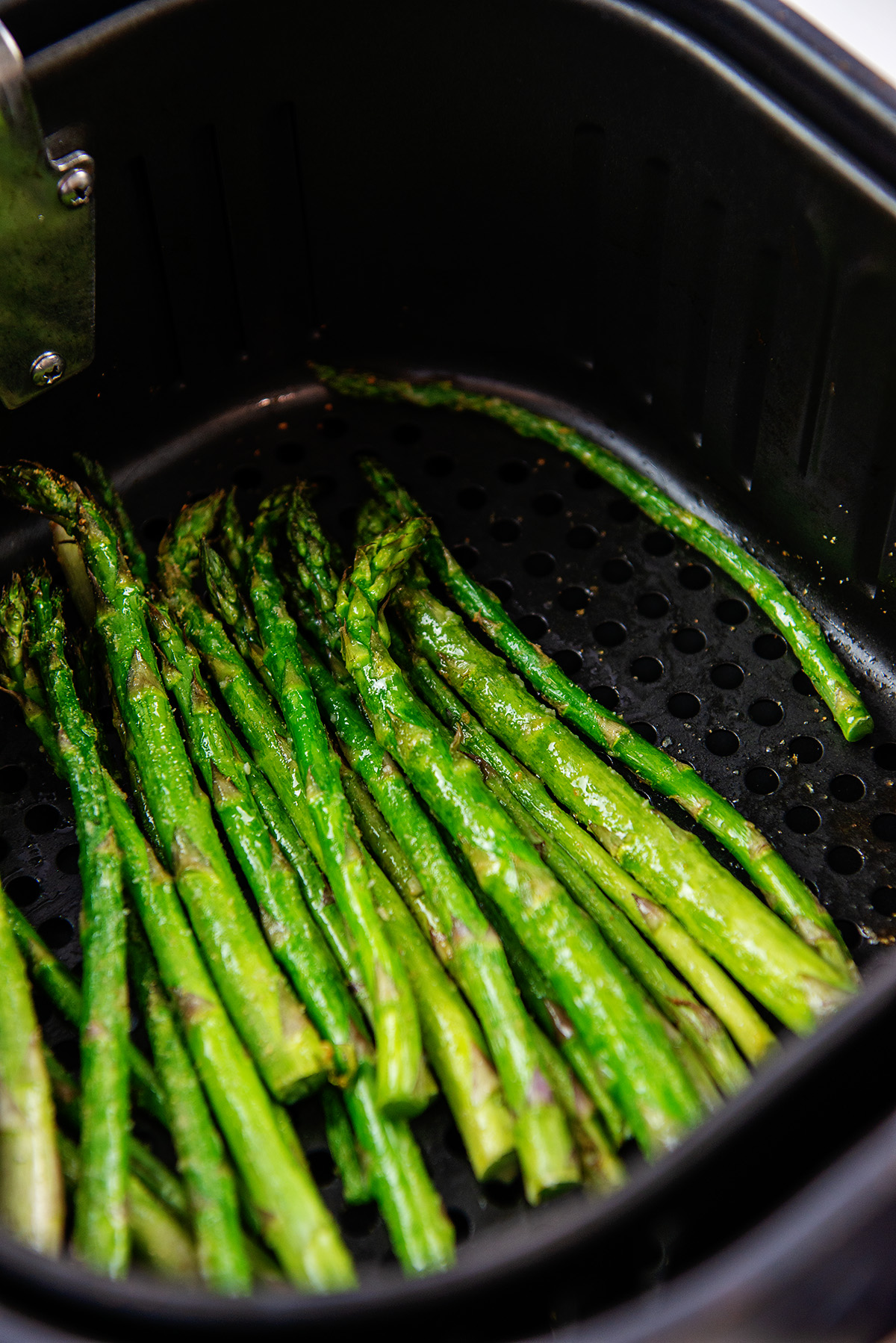 cooked asparagus in an air fryer basket