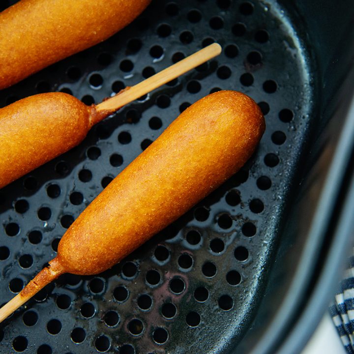 overhead view of corn dogs in air fryer basket.
