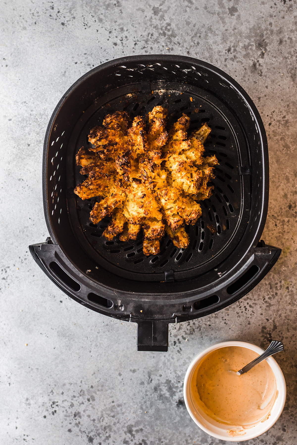 Overhead view of a blooming onion in an air fryer basket