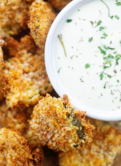 pile of fried pickles next to a bowl of ranch dip.