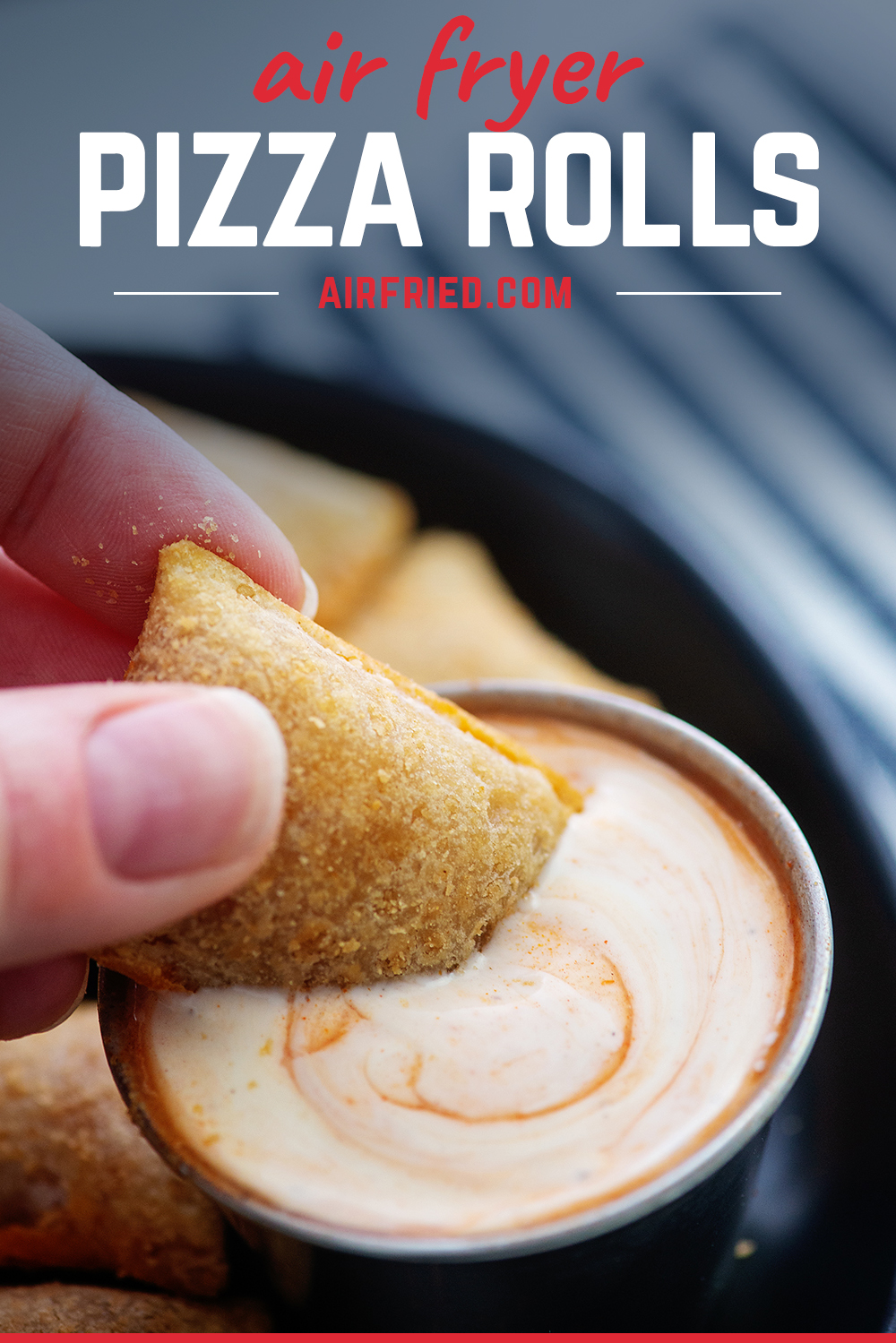 Close up of a woman dipping a pizza roll into a spicy ranch dip.