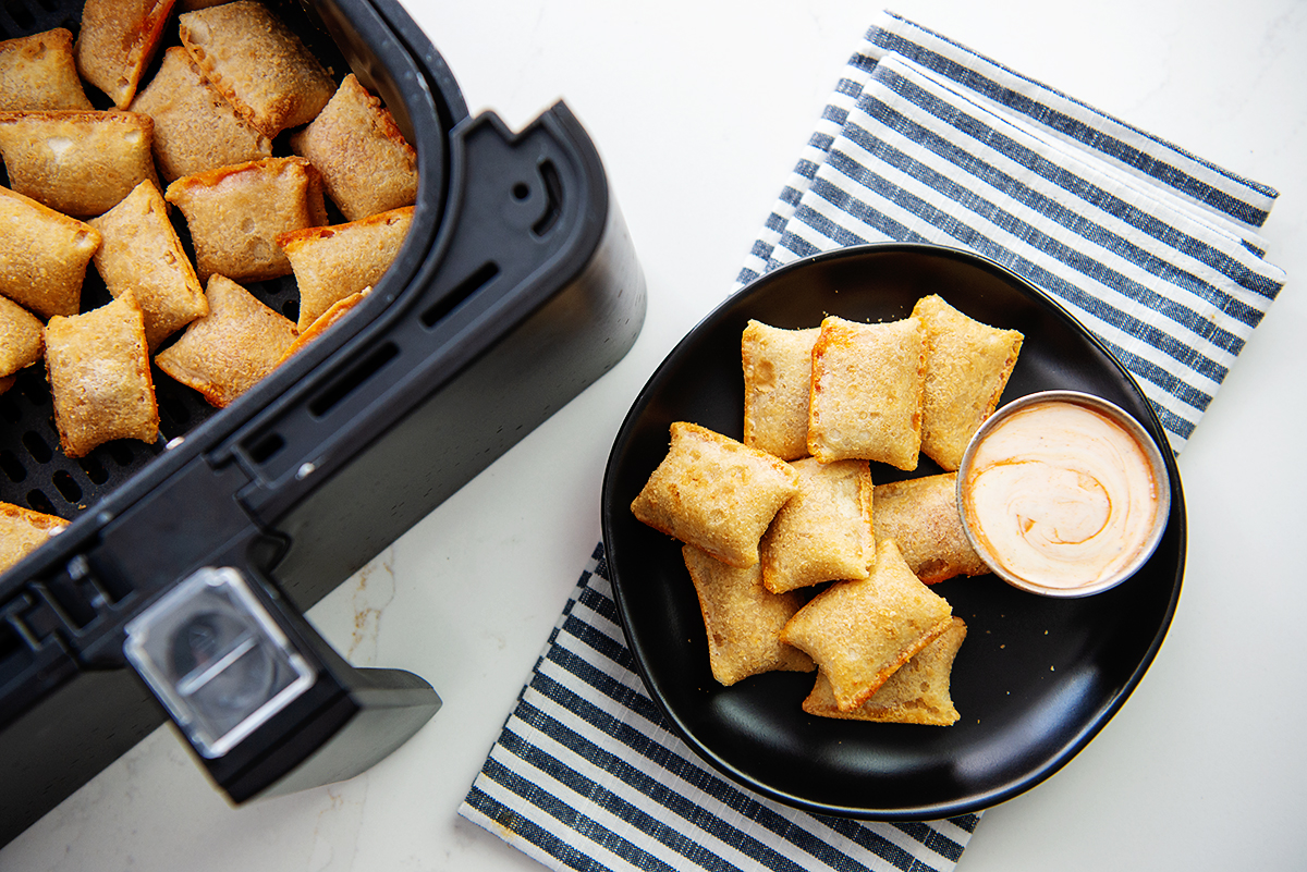 Pizza rolls on a black plate with a spicy ranch dip