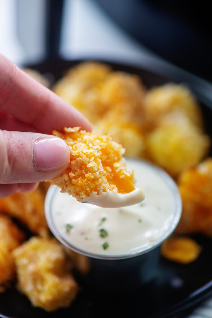 An air fried cheese curd with a bite out of it.