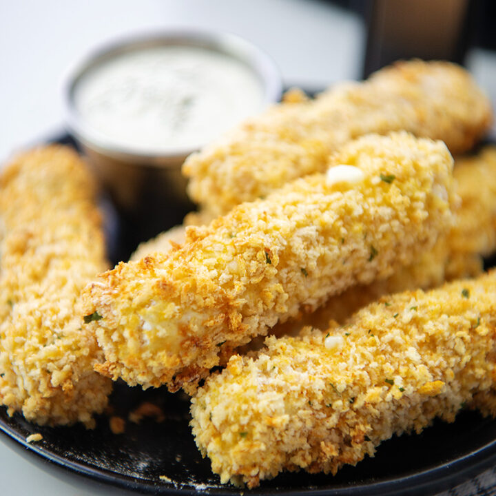 Cheese sticks stacked up on a black plate