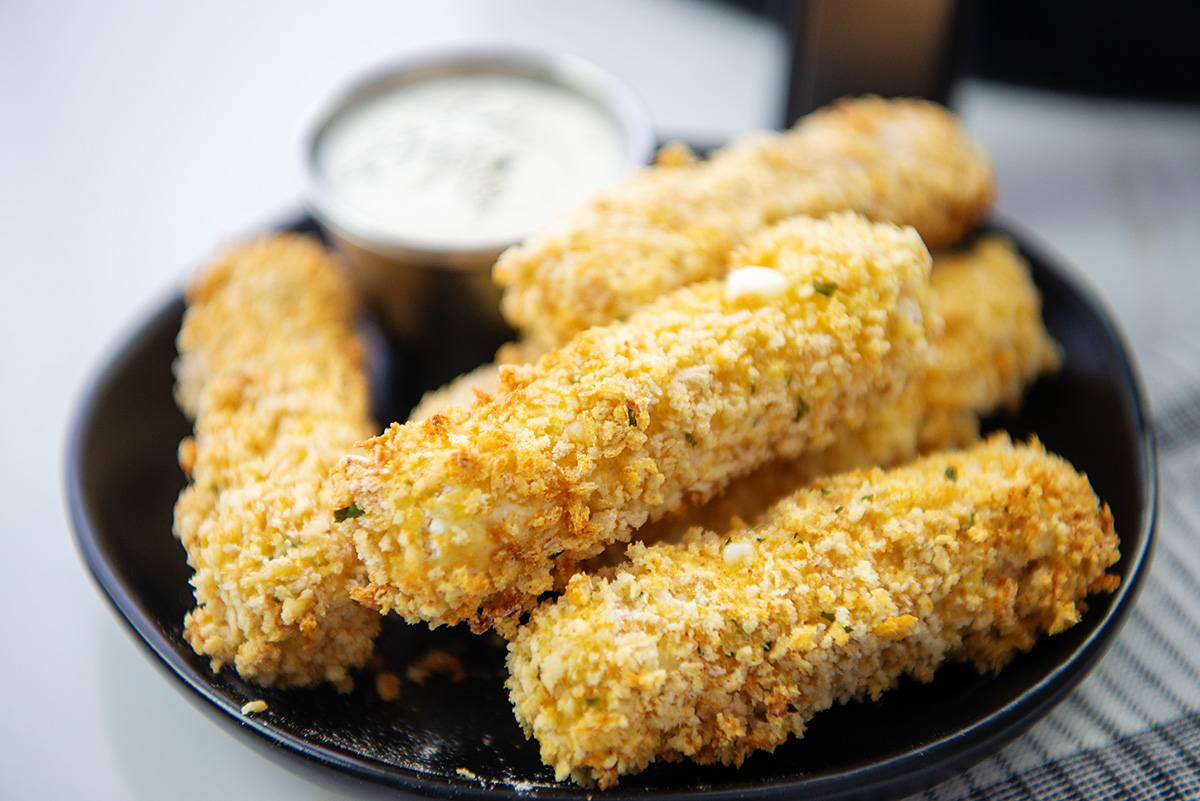 Cheese sticks stacked up on a black plate