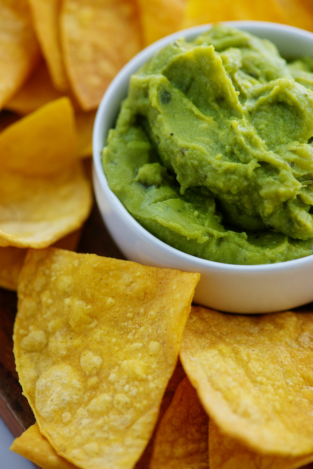 A cup of guacamole surrounded by tortilla chips