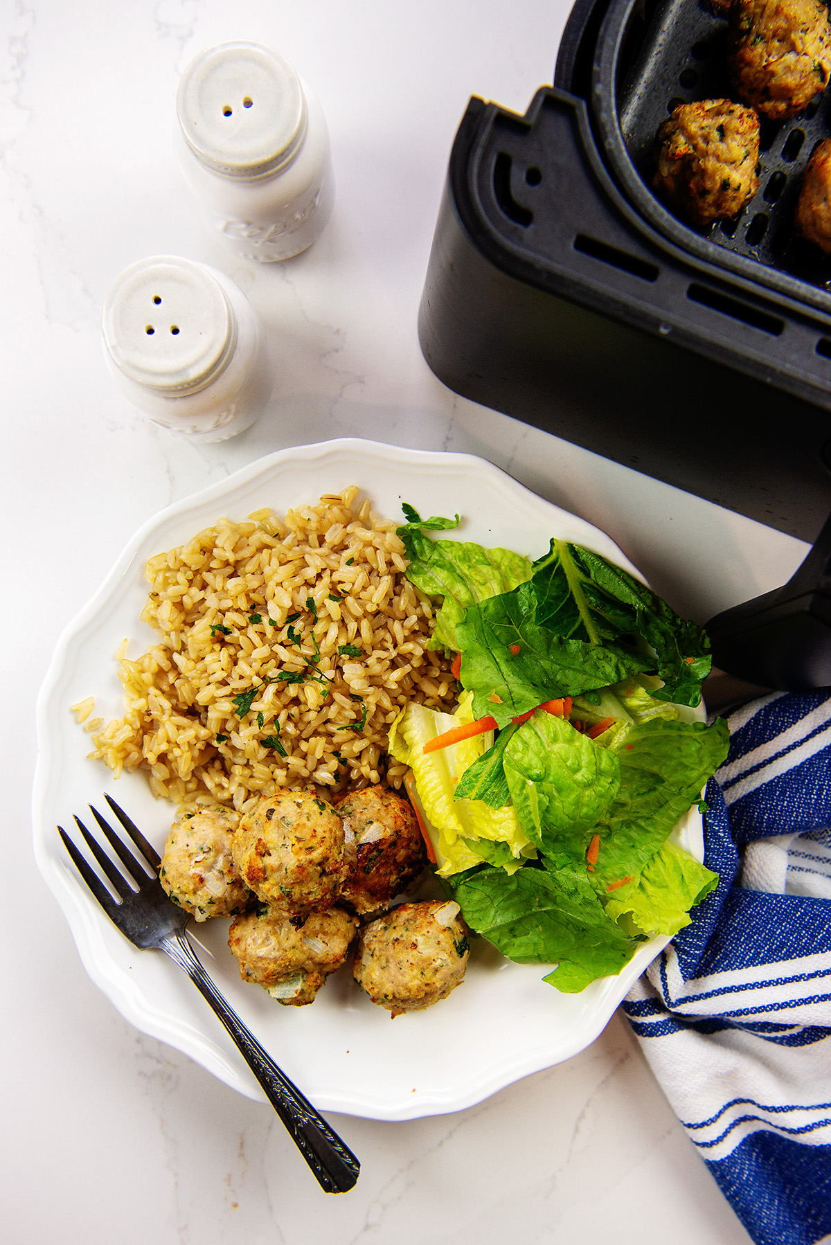 overhead view of a serving of turkey meatballs next to an air fryer basket