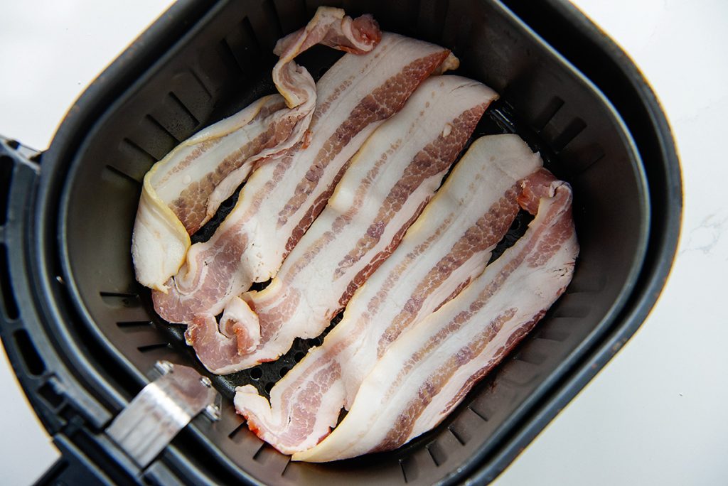 strips of bacon in air fryer basket.