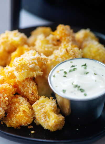 close up of cheese curds and ranch dressing on a black plate