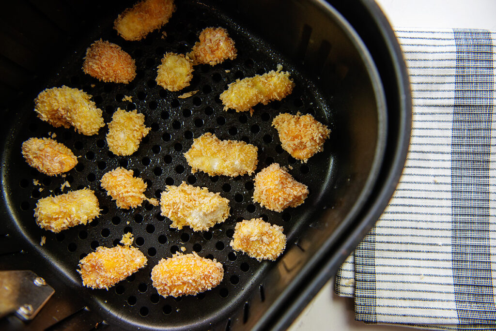 breaded cheese curds in an air fryer basket