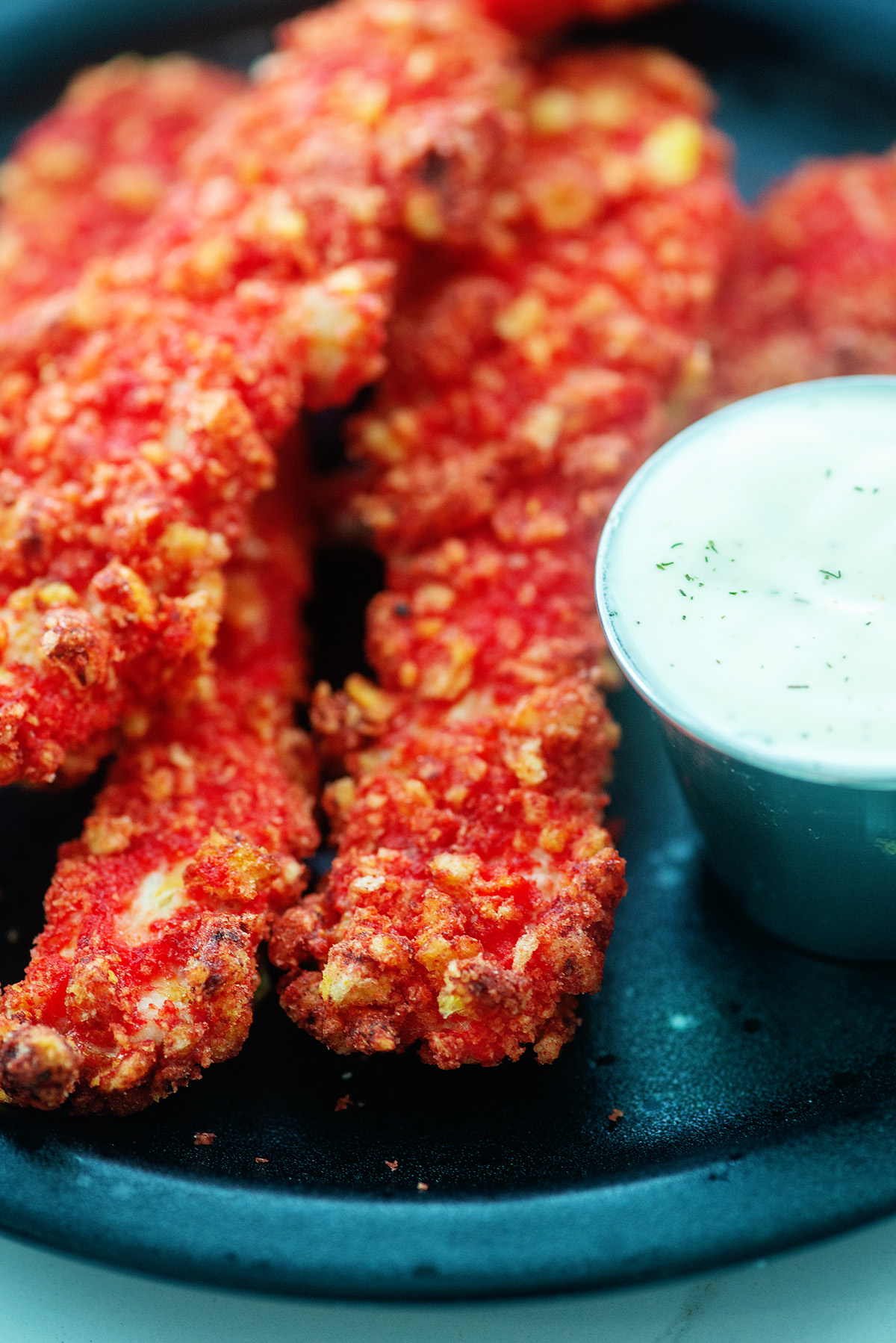 close up of chicken strips and ranch dressing on a plate.