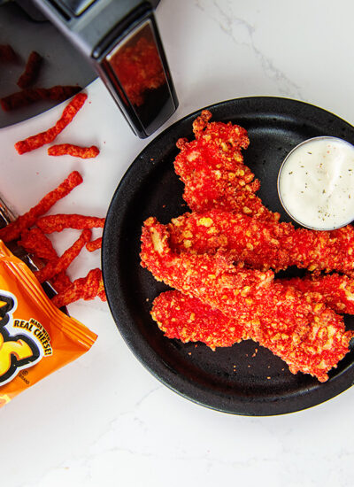 overhead view of cheetos spilling out of a bag next to a plate of chicken strips