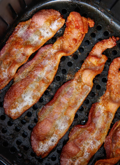 bacon slices in air fryer basket.