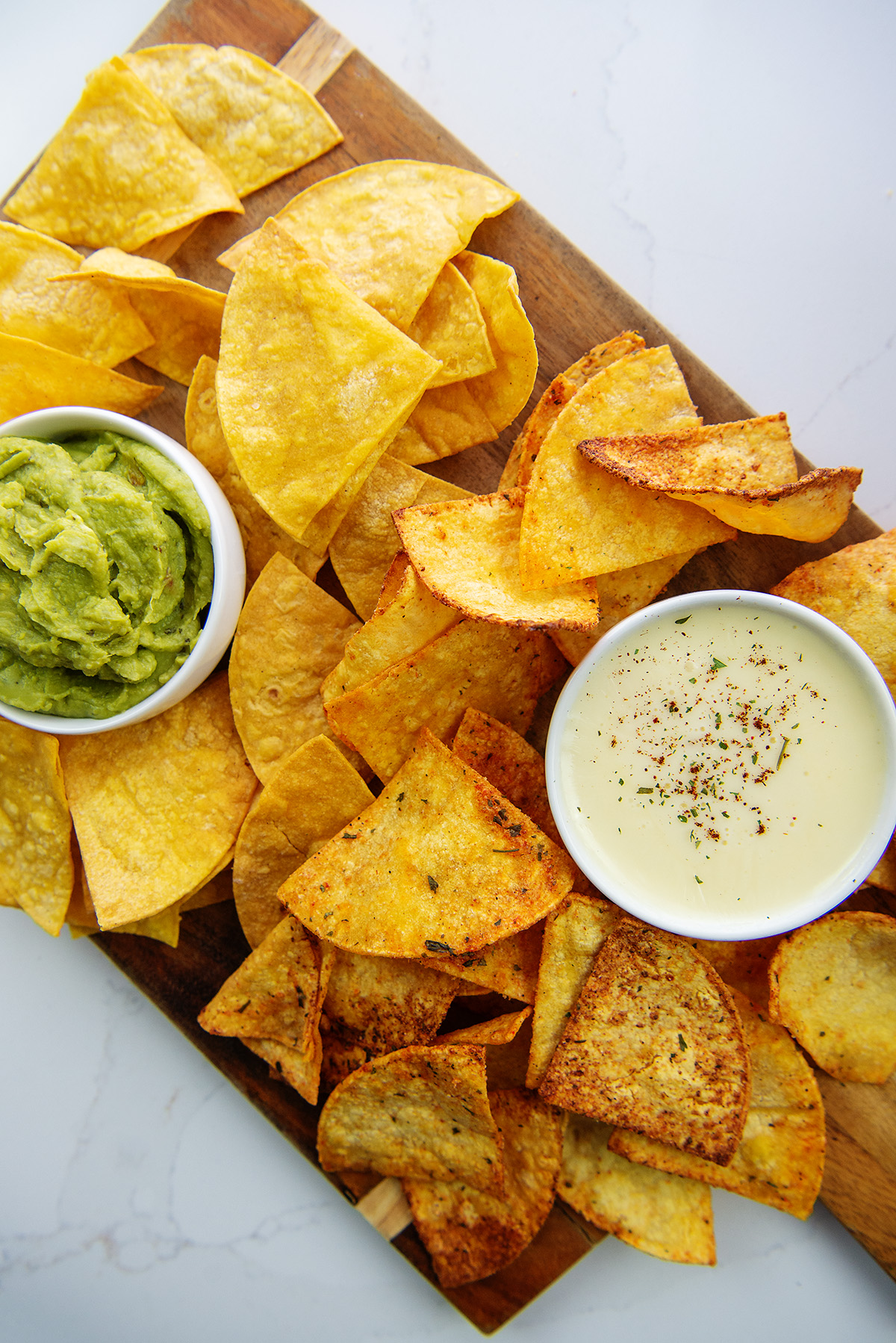 Cutting board with chips, guacamole, and queso dip