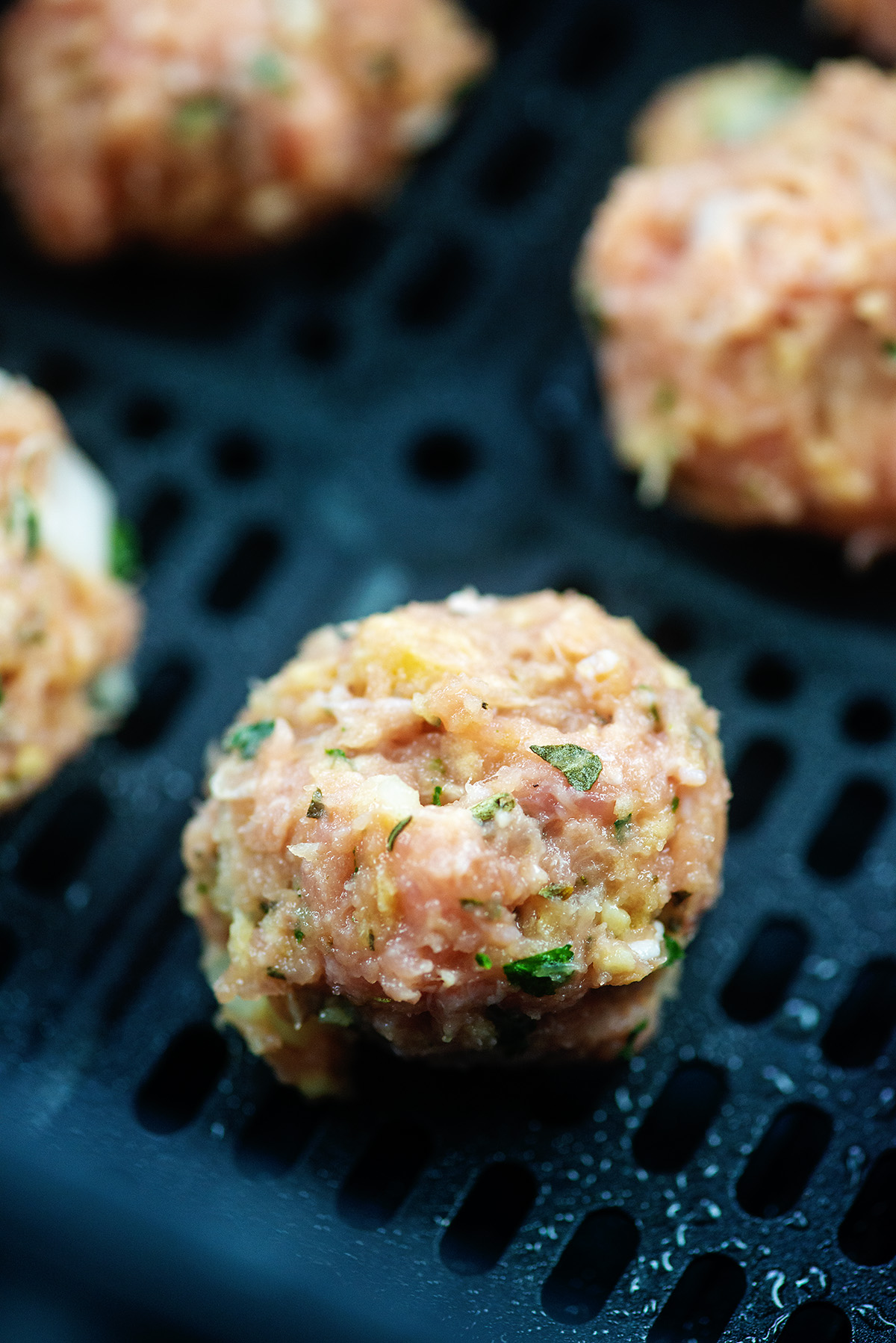 raw turkey meatballs in an air fryer basket