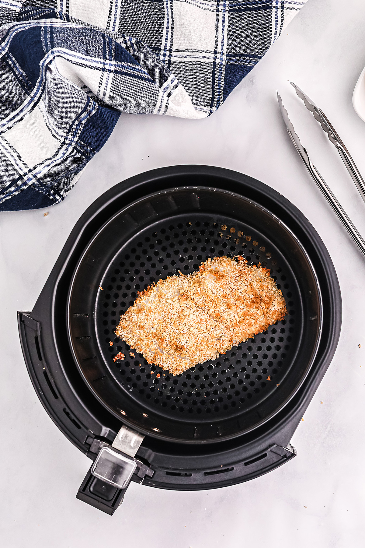 a breaded fish fillet in an air fryer basket