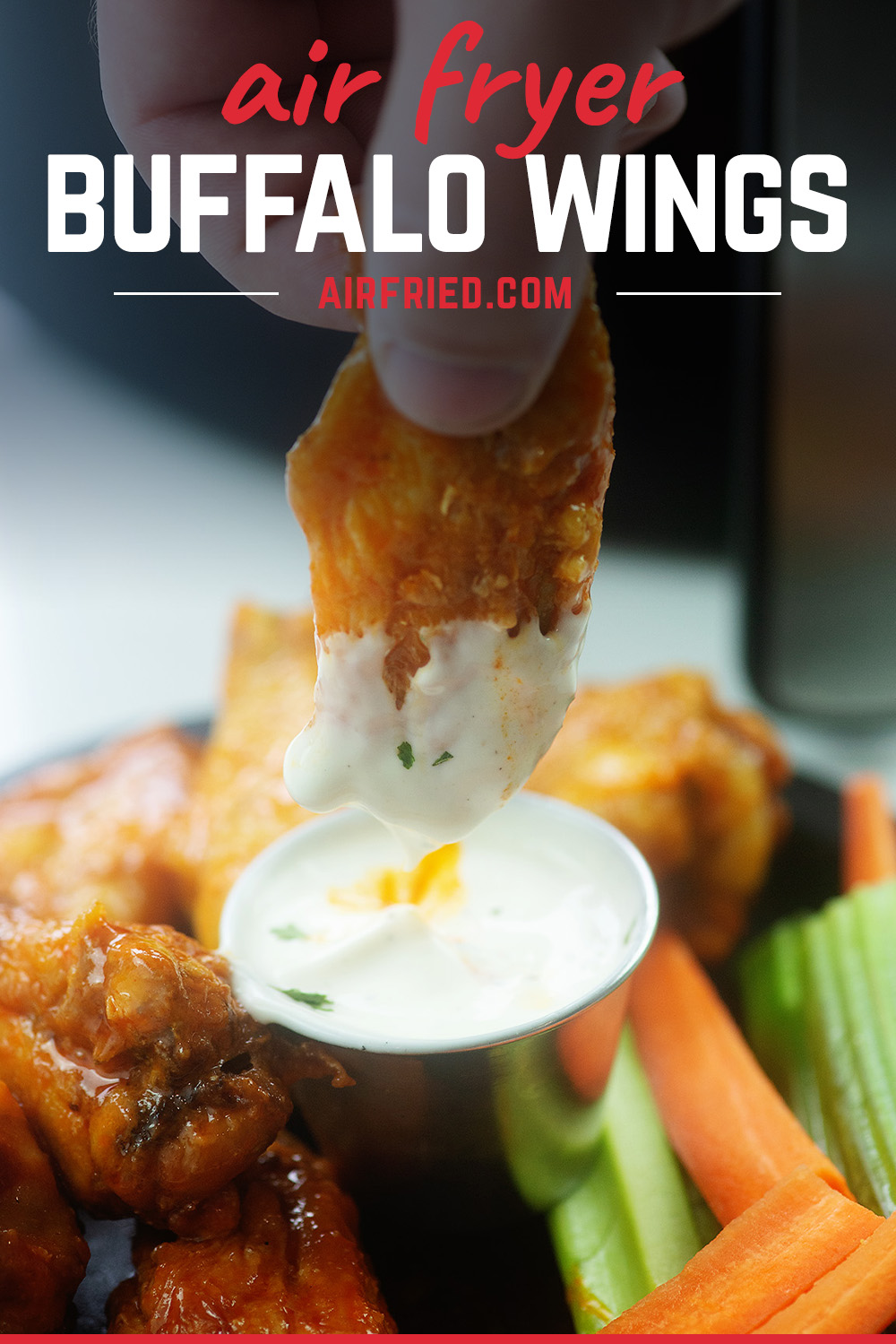 A chicken wing being dipped into ranch dressing