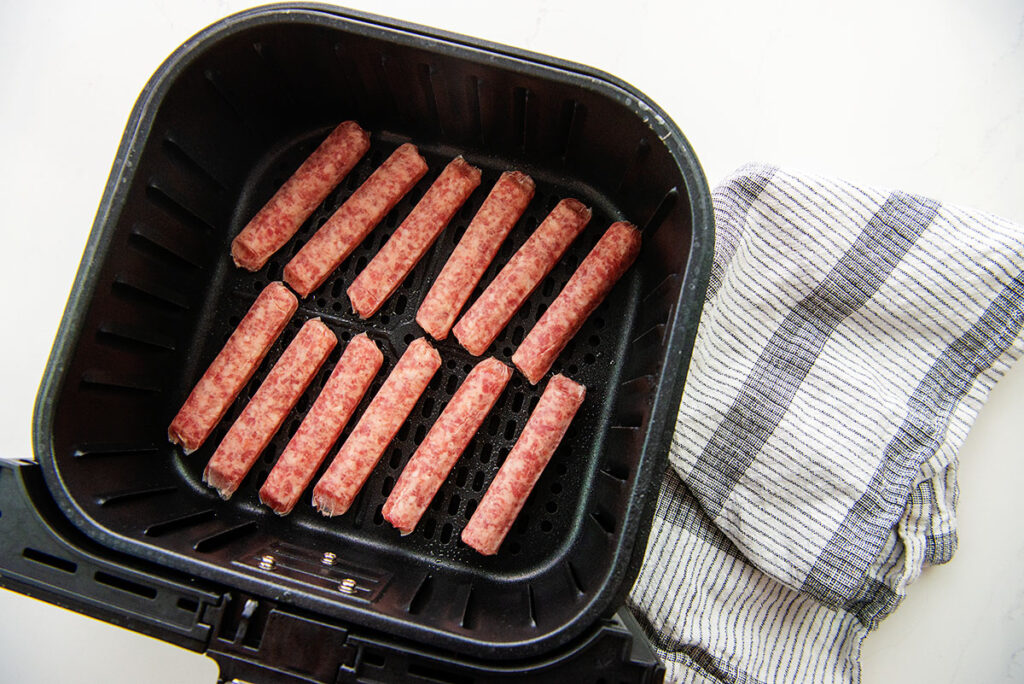 raw sausage links in an air fryer basket
