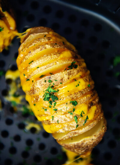 A cooked hasselback potato in an air fryer basket