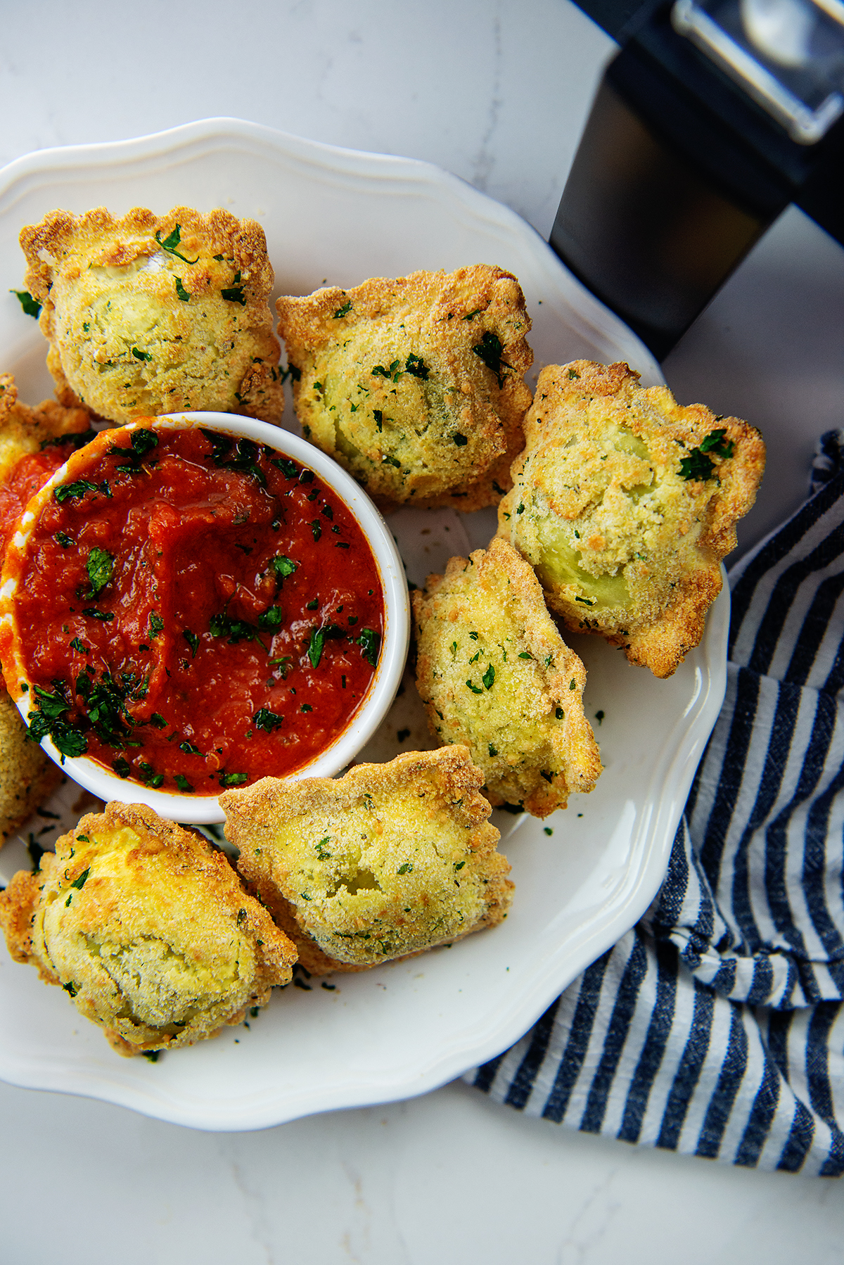 overhead view of air fried ravioli on plate with marinara sauce.