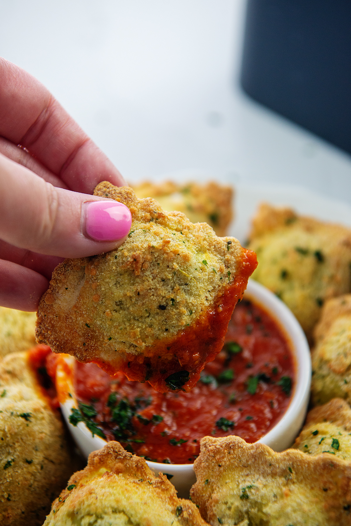 woman dipping a ravioli in marinara sauce.