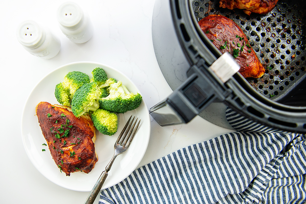 A plate of bbq chicken next to an air fryer