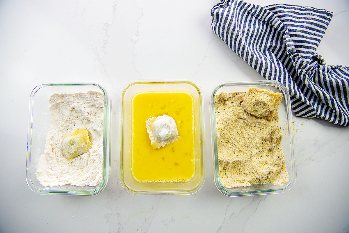 overhead view of ravioli being coated in flour, eggs, and bread crumbs.