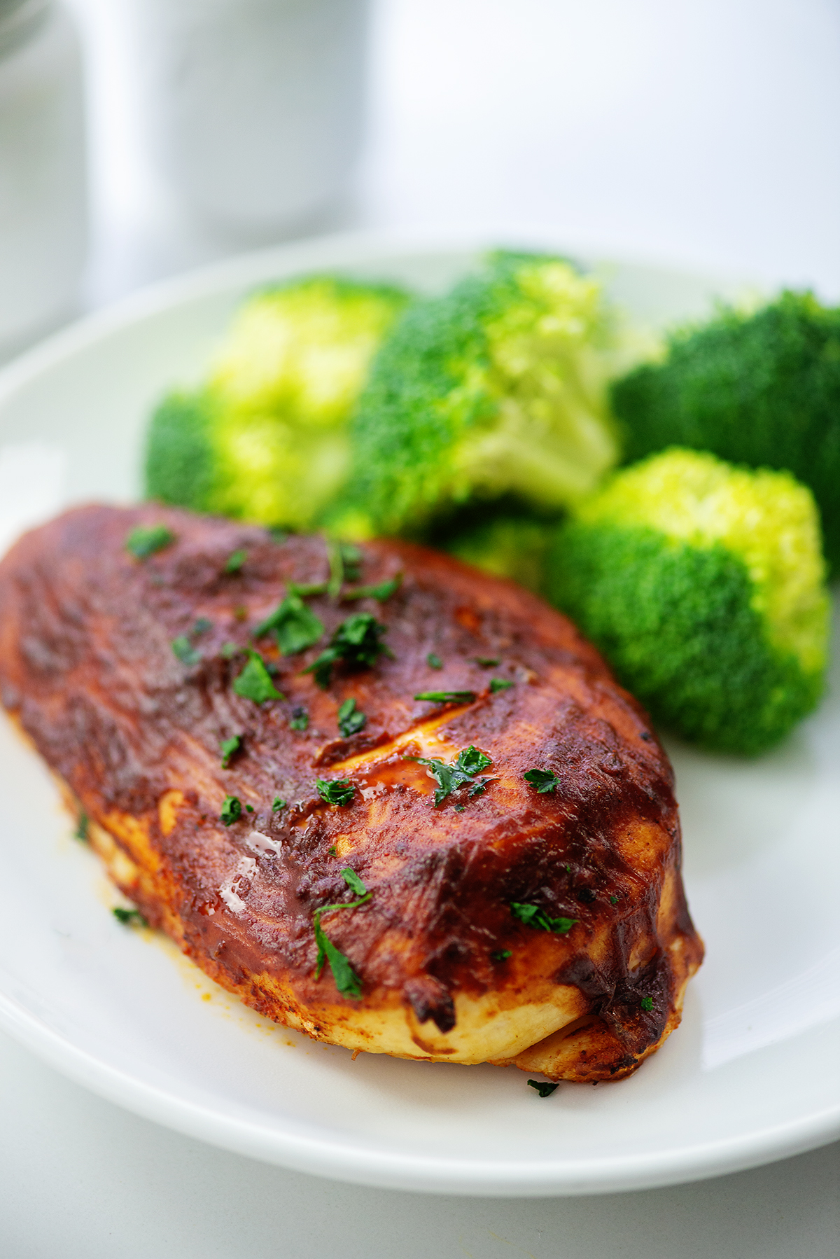 BBQ chicken and broccoli on a small white plate