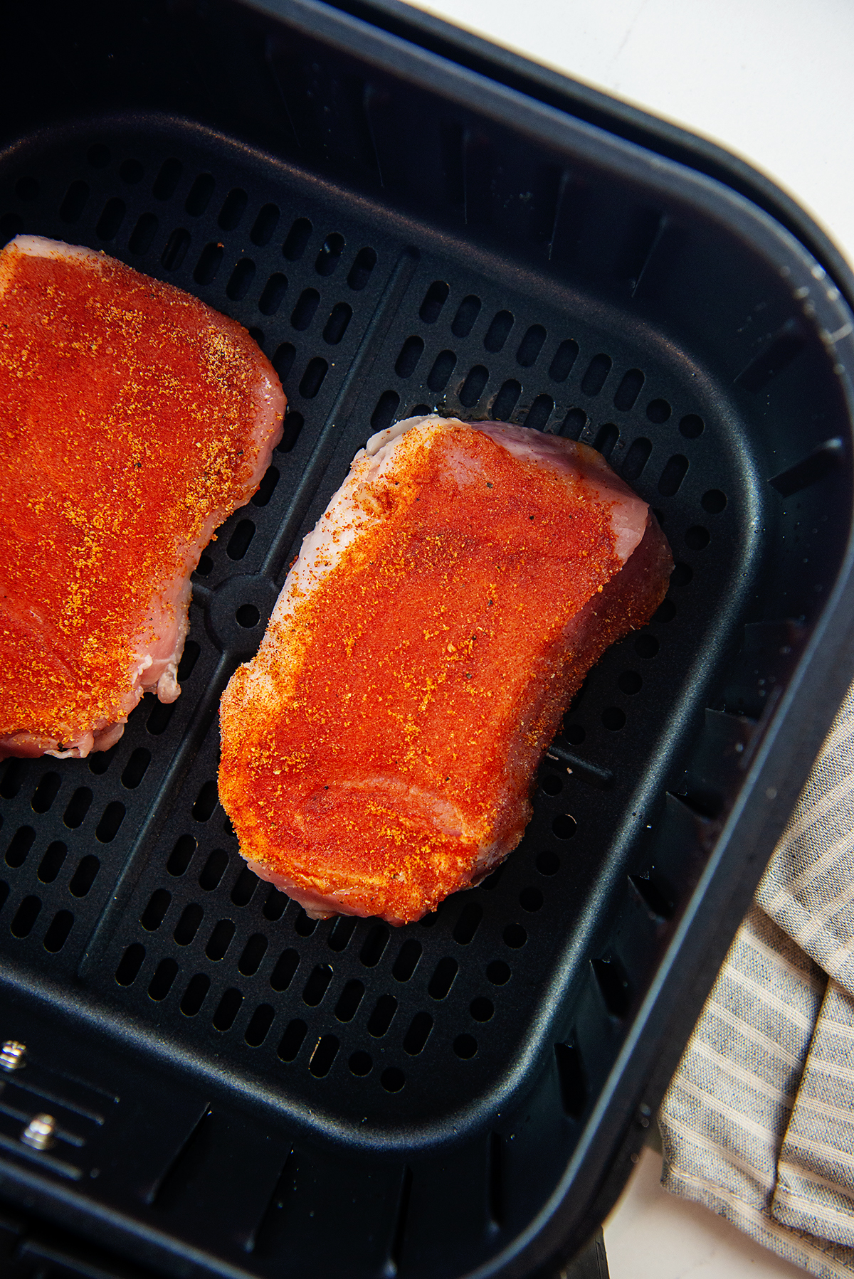 Raw, seasoned pork chops in an air fryer
