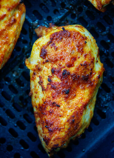 Close up of a chicken breast cooked in an air fryer basket