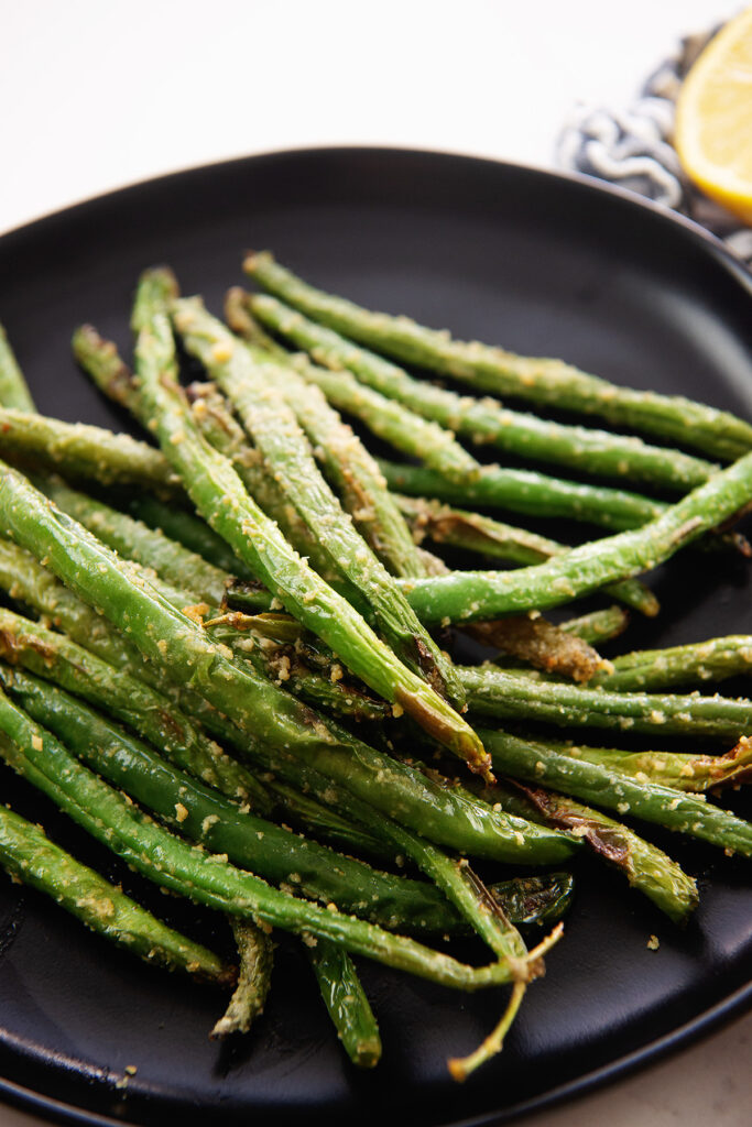 Close up of roasted green beans on a small black plate