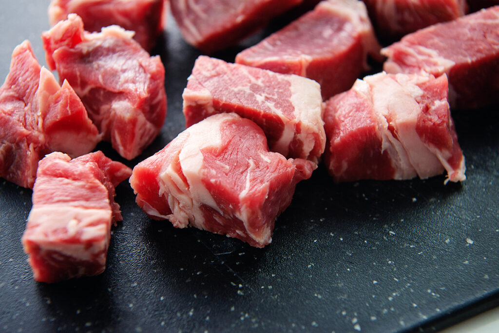 Raw steak chunks on a cutting board