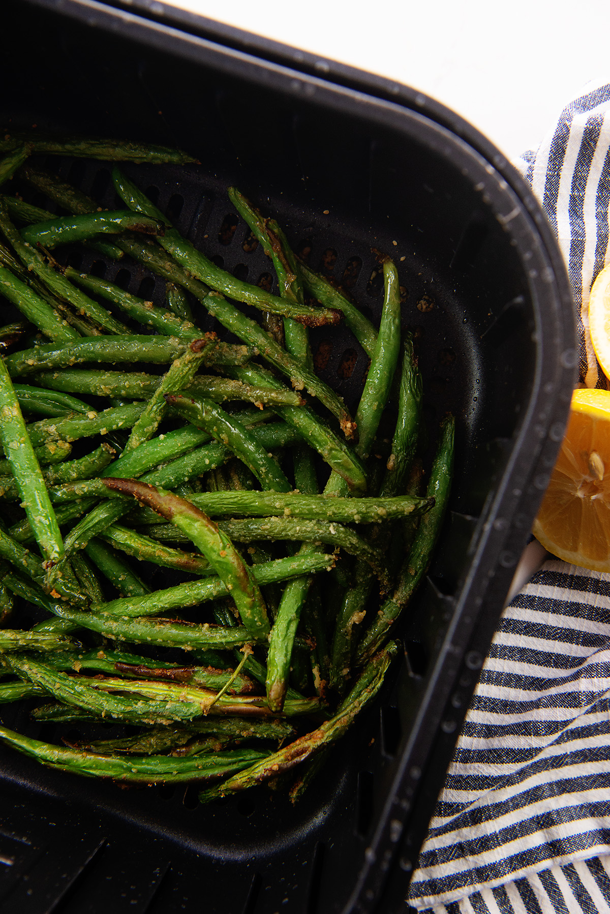 Overhead view of cooked green beans in an air fryer basket