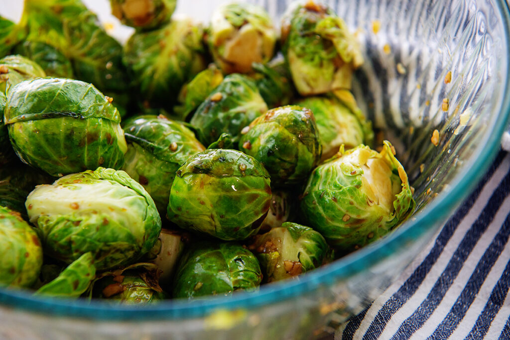 Raw brussels sprouts in a clear glass bowl