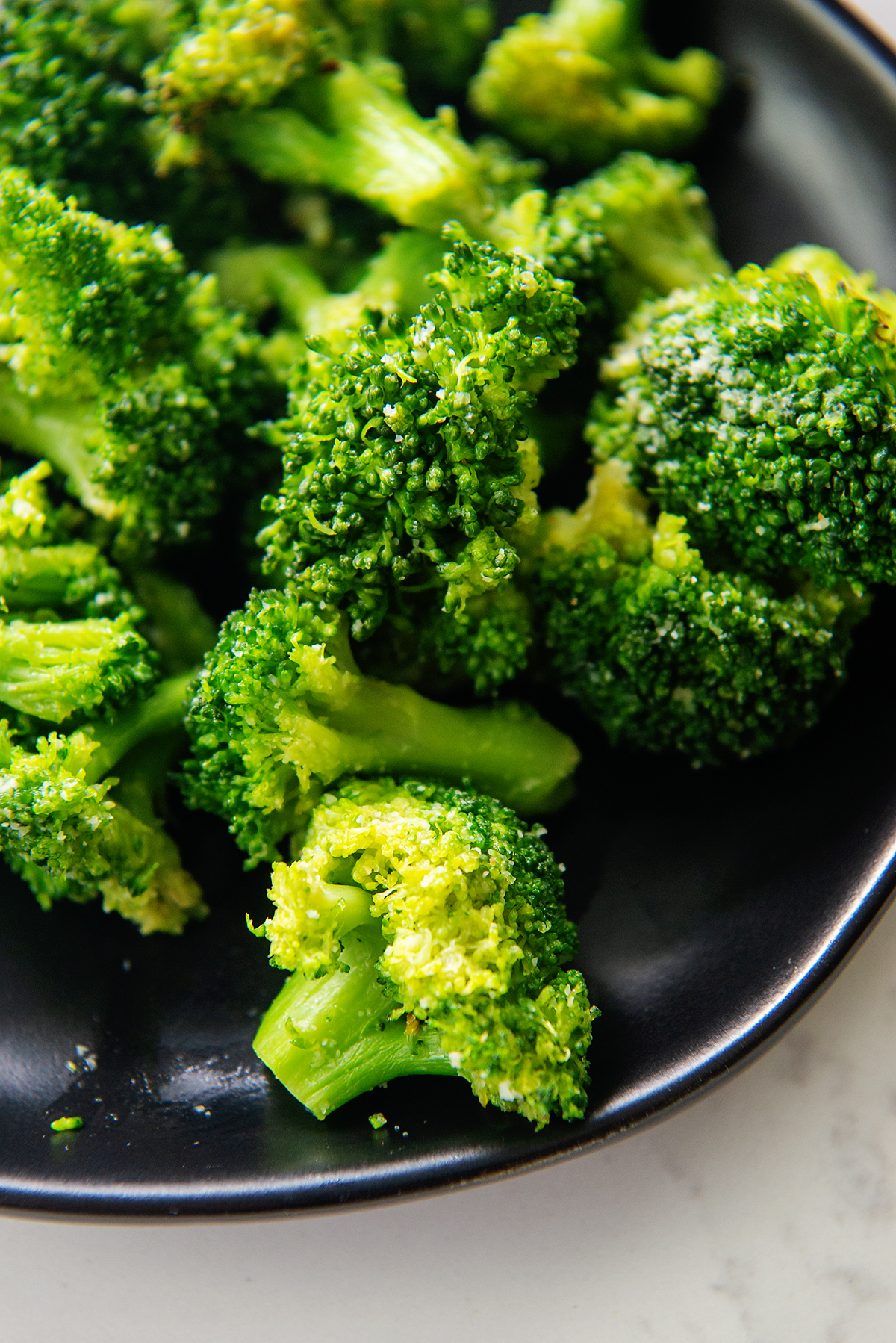 Close up of broccoli florets on a small black plate.