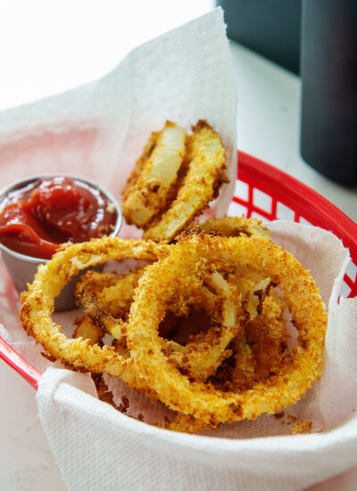 Onion rings in an appetizer basket with a cup of ketchup