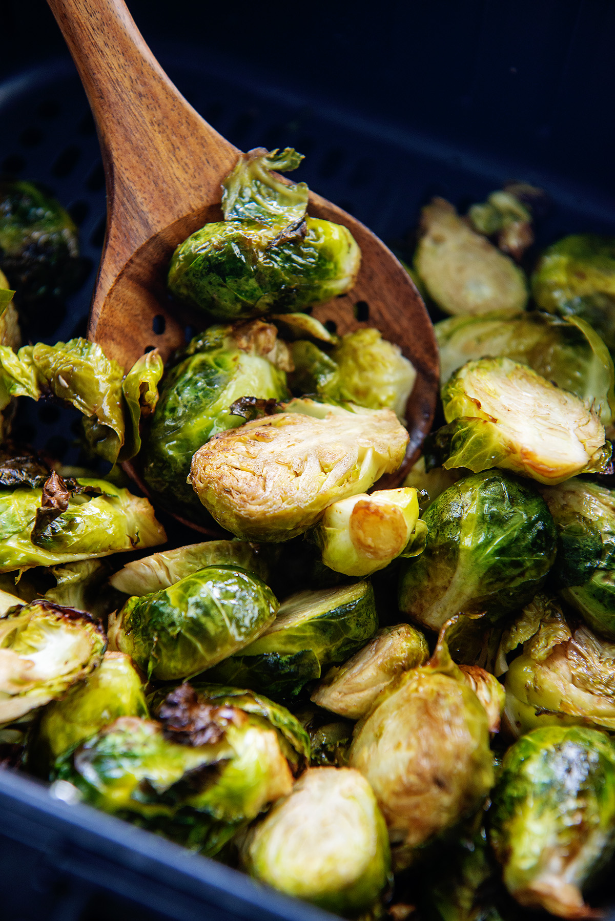 A wooden spoon dipping into a pile of brussels sprouts.