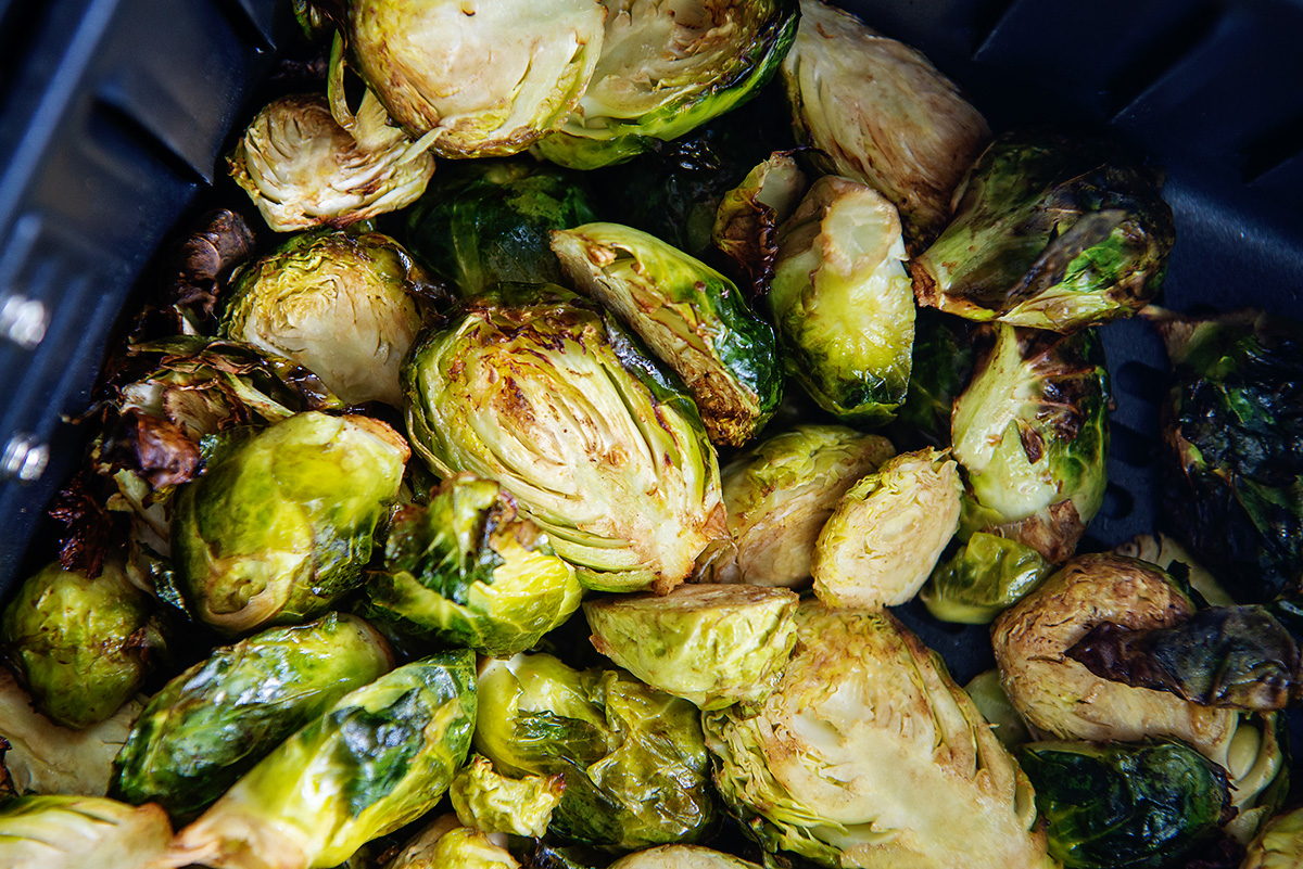 Close up of Brussels sprouts piled up in an air fryer basket