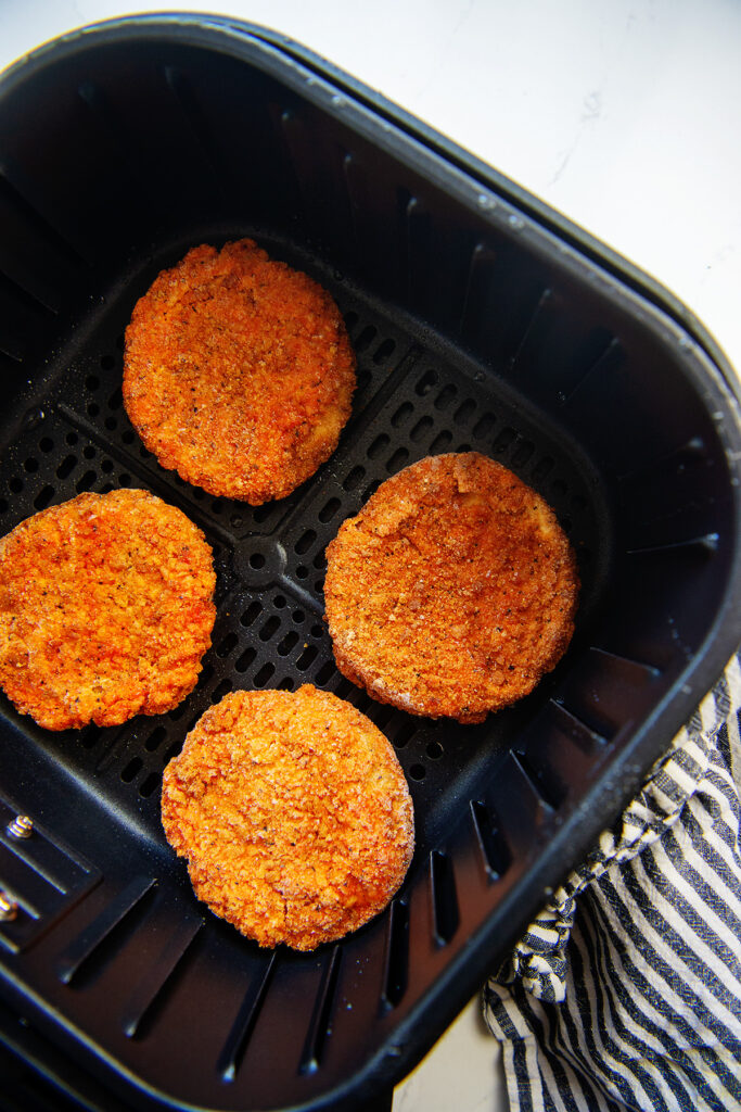 Overhead view of four chicken patties in an air fryer basket