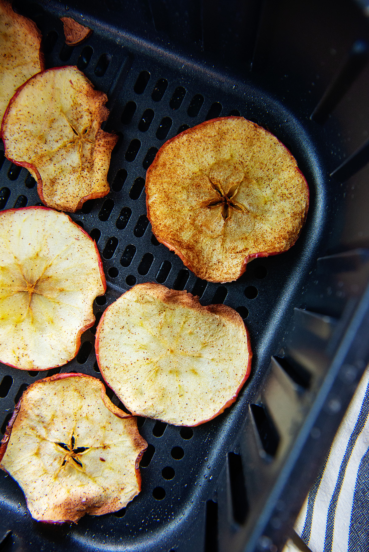 Cooked cinnamon apple chips in an air fryer basket