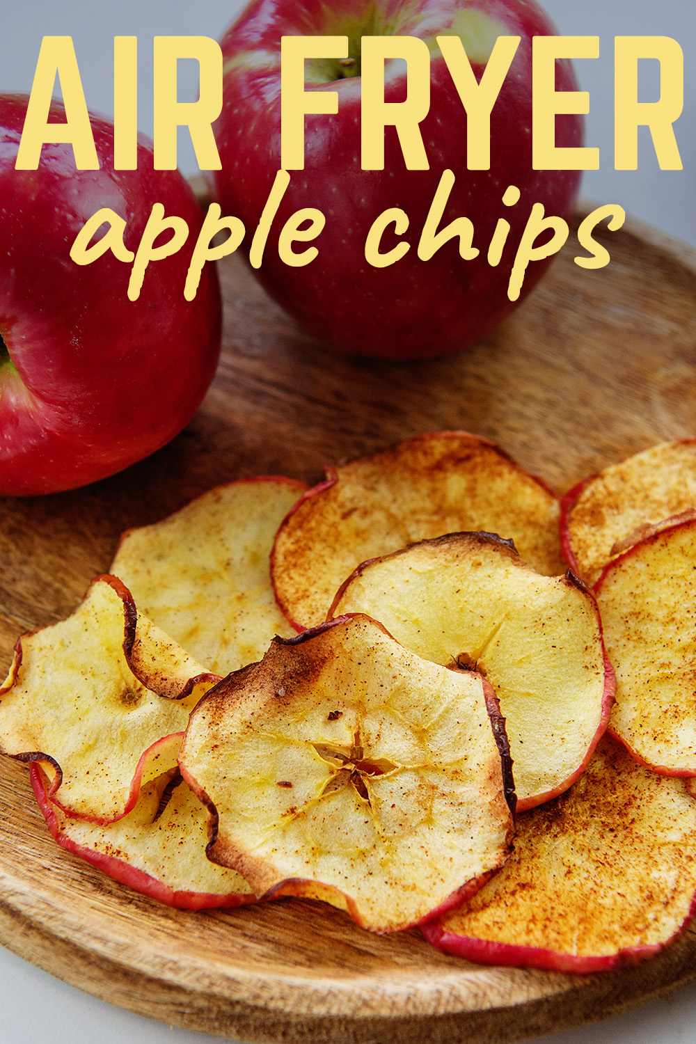 cooked apple chips on a plate in front of two apples