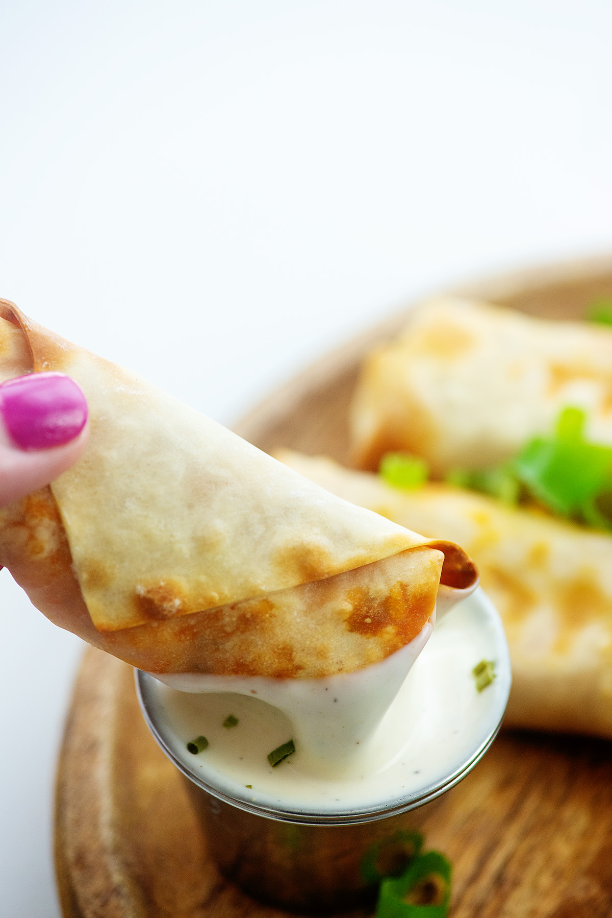 A woman dipping an egg roll into ranch dressing