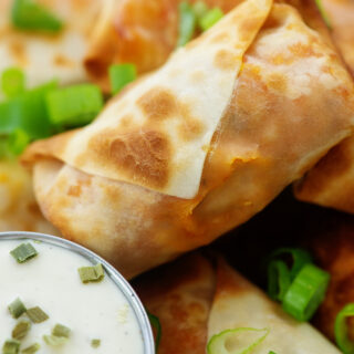 Close up of an egg roll next to ranch dressing