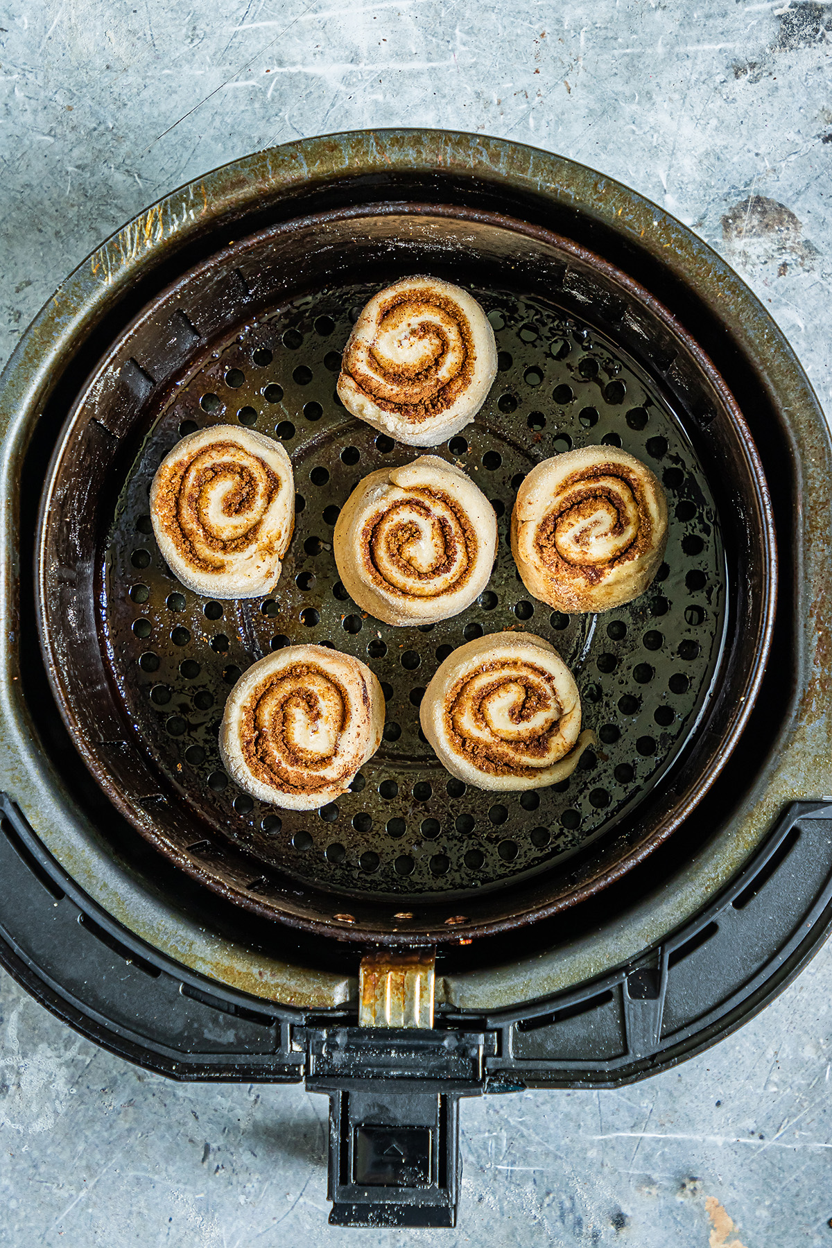 raw cinnamon roll dough in an air fryer basket