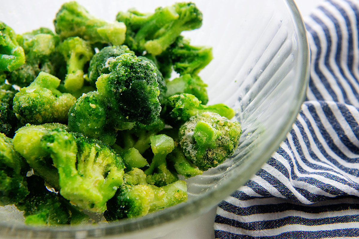 Seasoned broccoli in a clear glass bowl.