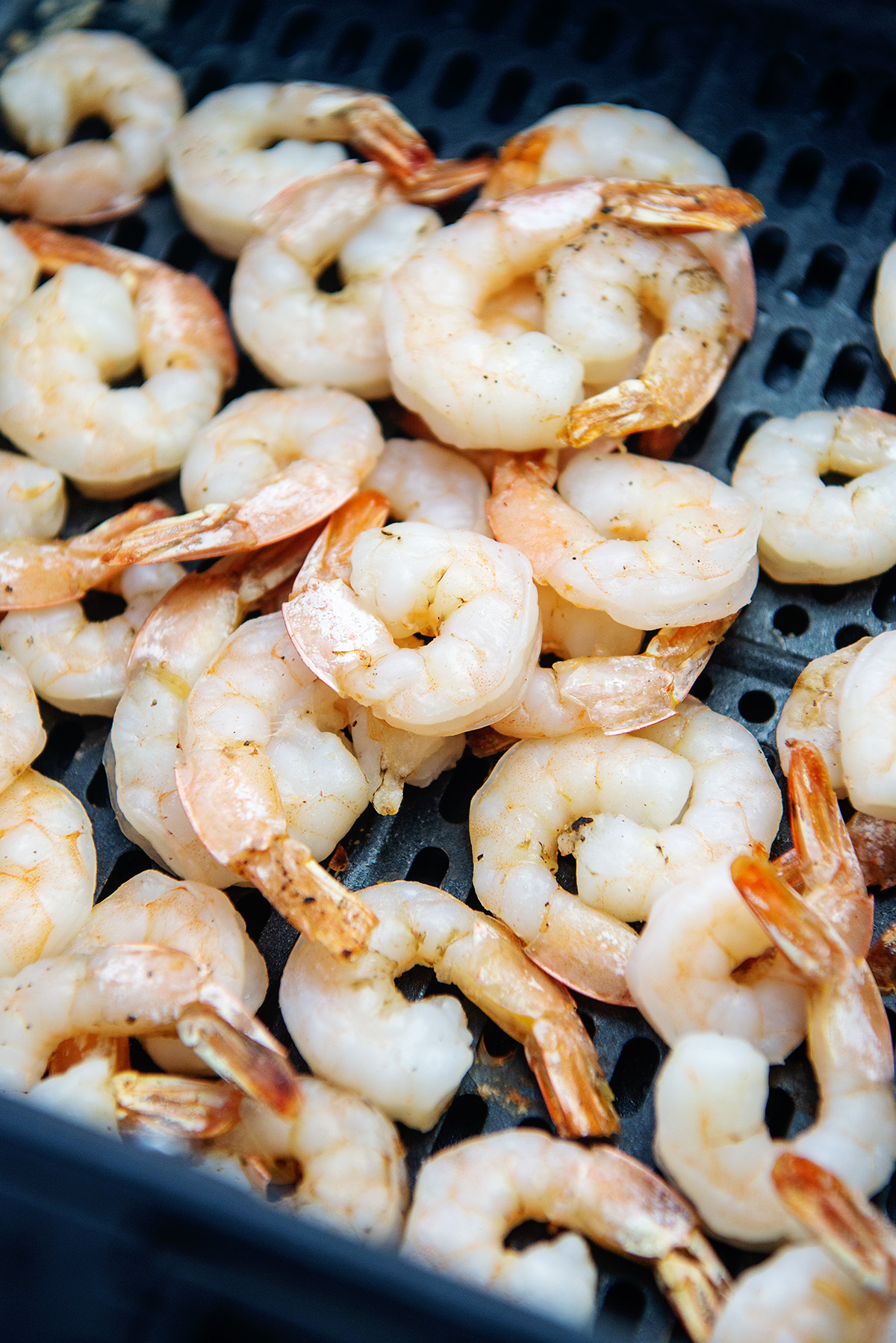 cooked shrimp in air fryer basket.