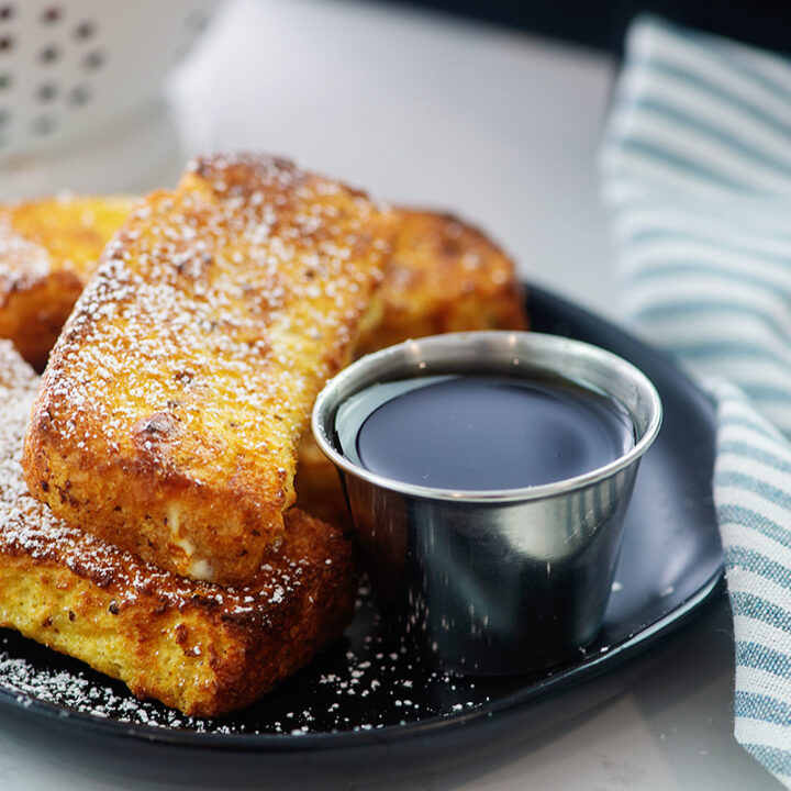 Close up of French toast sticks on a small black plate